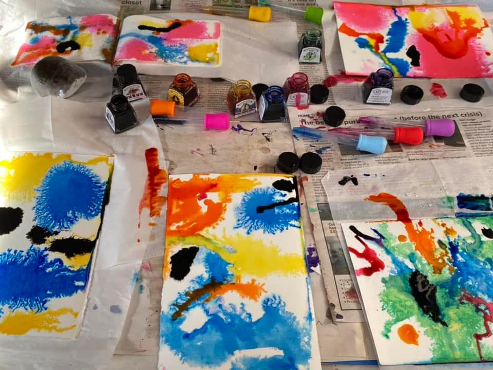 an image of paints and colorfully painted papers on a work table